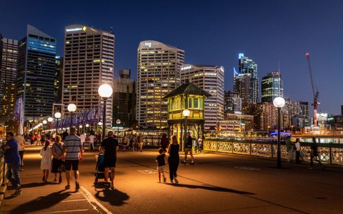 23rd December 2018, Sydney NSW Australia : People walking on Pyrmont bridge at night with view on the control cabin tower in middle of the swing bridge in Sydney NSW Australia